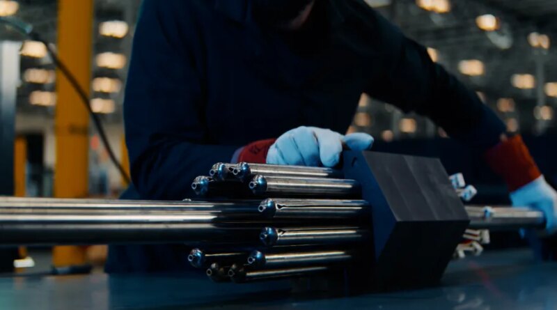 A person handles a nuclear fuel assembly.