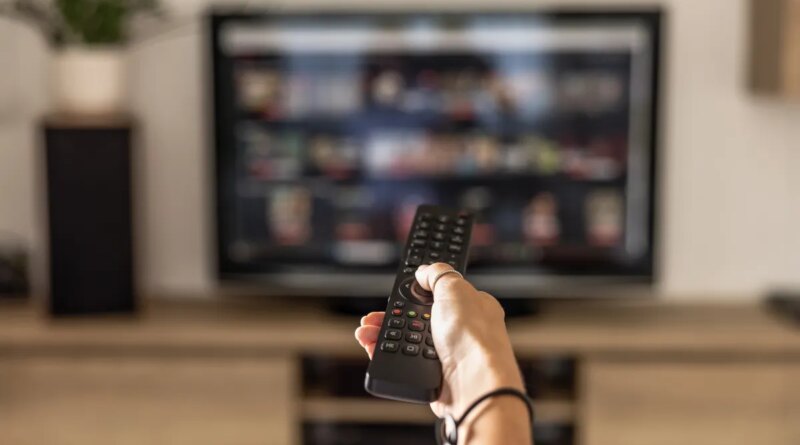 hand holding remote pointed at TV