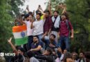 Abhijeet Dipke, head of the Cockroach Janta Party (CJP), celebrates with supporters who stand on an elevated platform holding their hands up in triumph 