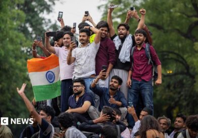 Abhijeet Dipke, head of the Cockroach Janta Party (CJP), celebrates with supporters who stand on an elevated platform holding their hands up in triumph 