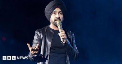 Diljit Dosanjh kicks off his Aura World Tour at BC Place on April 23, 2026, in Vancouver, British Columbia, Canada. He is wearing a black jacket over a black t-shirt and sporting a black turban, as he speaks on a microphone from the stage.