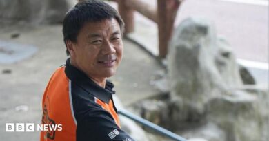 Wang Jibing in an orange polo shirt smiling at the camera