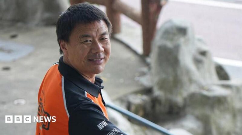 Wang Jibing in an orange polo shirt smiling at the camera
