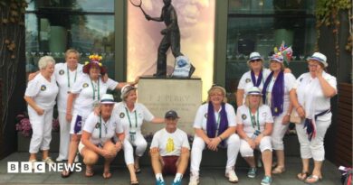 Geoff Hughes is sitting in the middle of a photo in front of a Fred Perry statue surrounded by members of the Andy Murray fan group The Murraynators