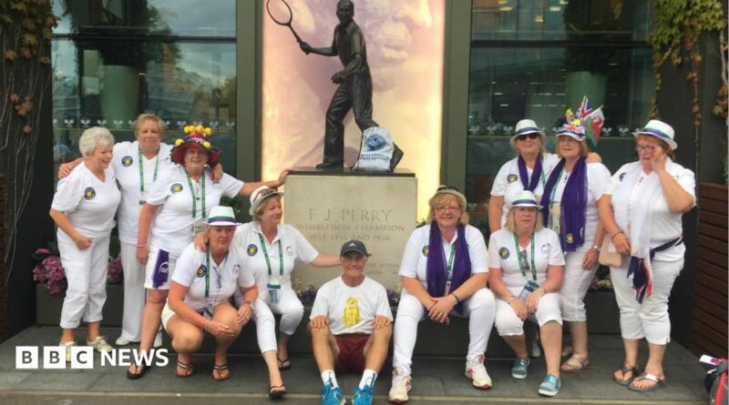 Geoff Hughes is sitting in the middle of a photo in front of a Fred Perry statue surrounded by members of the Andy Murray fan group The Murraynators