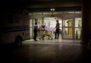 a person wheeled in on an ambulance stretcher outside of a U.S. emergency room at night