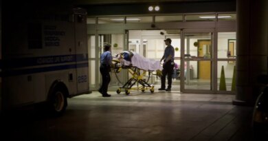 a person wheeled in on an ambulance stretcher outside of a U.S. emergency room at night