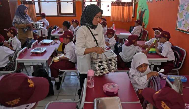 Members of school committee distribute meals to students during the kick off of President Prabowo Subianto's ambitious free meal program to feed children and pregnant women nationwide despite critics saying that its required logistics could hurt Indonesia's state finances and economy, at an elementary school in Depok, West Java, Indonesia, Monday, Jan. 6, 2025. (AP Photo/Dita Alangkara)