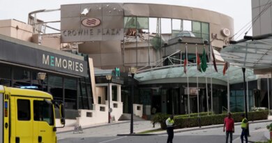 Security and civil defense workers stand outside the damaged Crown Plaza hotel, following an Iranian military strike, in Manama on March 1, 2026.
