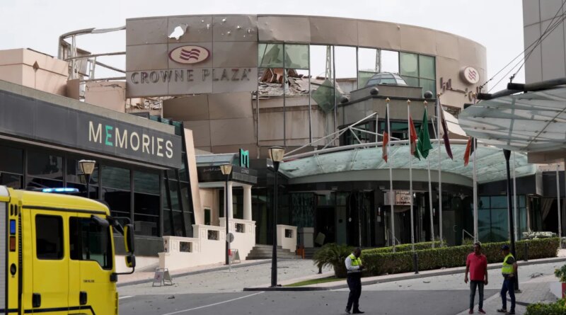 Security and civil defense workers stand outside the damaged Crown Plaza hotel, following an Iranian military strike, in Manama on March 1, 2026.
