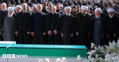 Iranian President Masoud Pezeshkian, Iran's Parliament speaker Mohammad Baqer Qalibaf and Chief Justice of Iran Gholam-hossein Mohseni Ejei with officials attend a prayer during a public farewell ceremony to pay their respects to late Supreme Leader Ayatollah Ali Khamenei. A large crowd can be seen in the background as everyone stands looking at the coffin