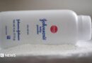 A bottle of Johnson and Johnson Baby Powder is seen in a photo illustration placed on its side on top of some white baby powder