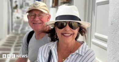 Karen Carter, pictured with her husband Alan. She is wearing dark glasses, a black and white sun hat and a white and striped shirt. 
