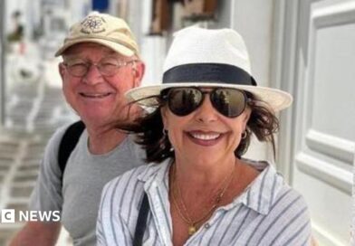 Karen Carter, pictured with her husband Alan. She is wearing dark glasses, a black and white sun hat and a white and striped shirt. 