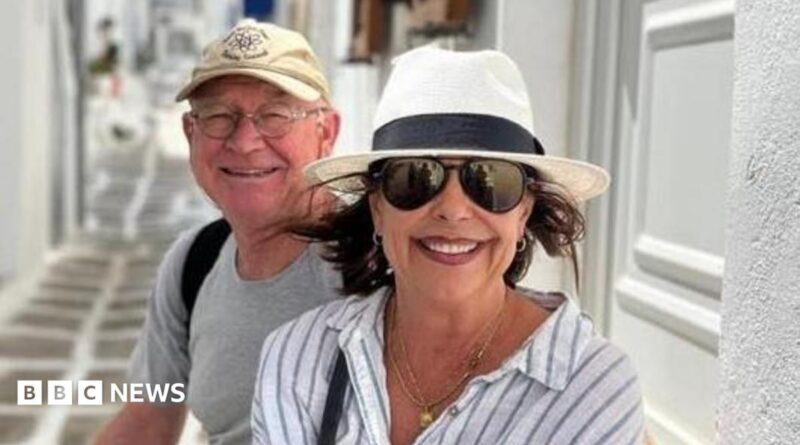 Karen Carter, pictured with her husband Alan. She is wearing dark glasses, a black and white sun hat and a white and striped shirt.