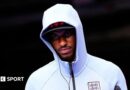 Marcus Rashford wearing a white England zip-up top, hood pulled up over his head