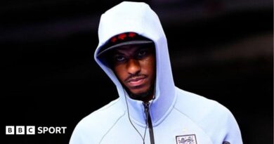 Marcus Rashford wearing a white England zip-up top, hood pulled up over his head