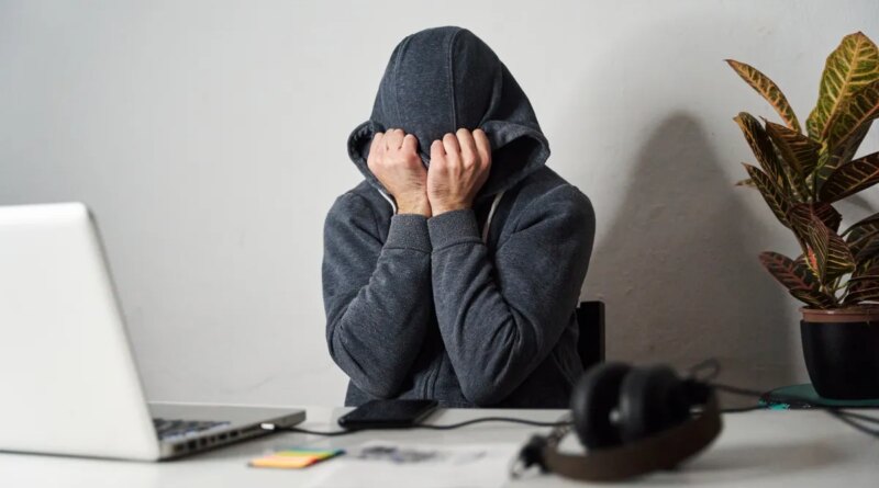 Man covering his face with a hood while working from home.