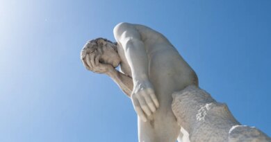 Man facepalming statue under the sun in the Tuileries garden.