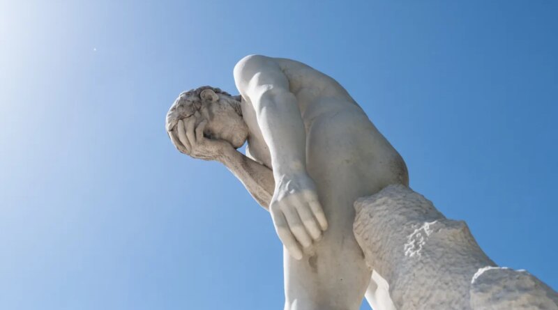 Man facepalming statue under the sun in the Tuileries garden.