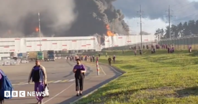 people walk away from a burning warehouse