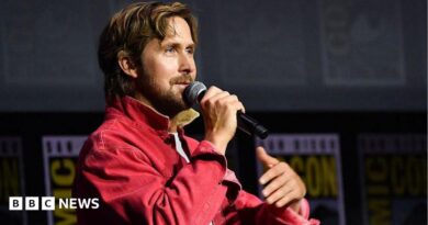 Ryan Gosling speaking into microphone on stage at San Diego Comic-Con