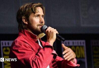 Ryan Gosling speaking into microphone on stage at San Diego Comic-Con