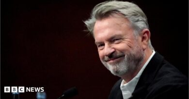 Sam Neill walking through a Jurassic forest, leading two children