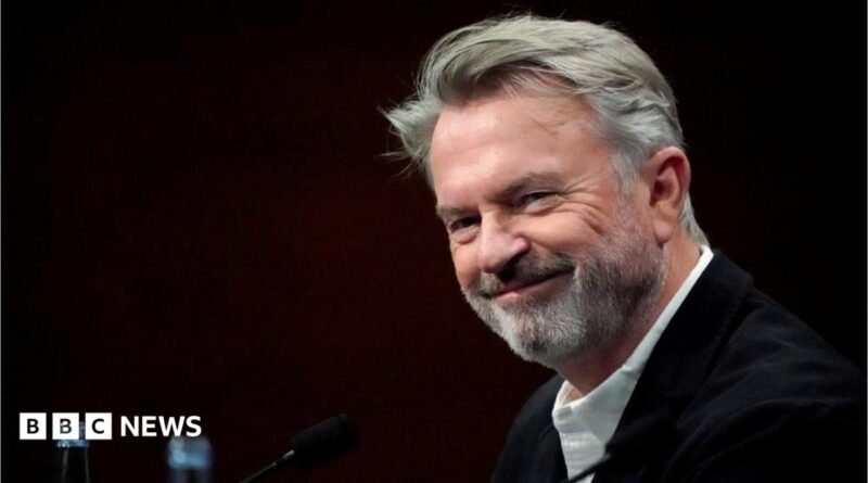 Sam Neill walking through a Jurassic forest, leading two children