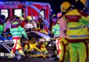 A number of emergency services personnel standing near an ambulance, with a person on a stretcher