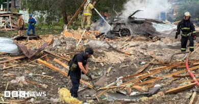 Emergency services clear through the rubble following a Russian missile strike just outside of Kyiv. Firefighters can be seen extinguishing a car fire in the background