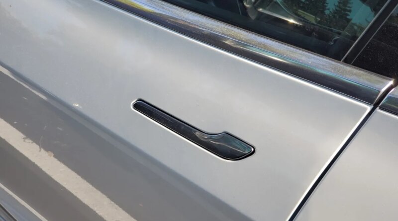 Close-up of flush-mounted, retracting door handle on Tesla automobile.