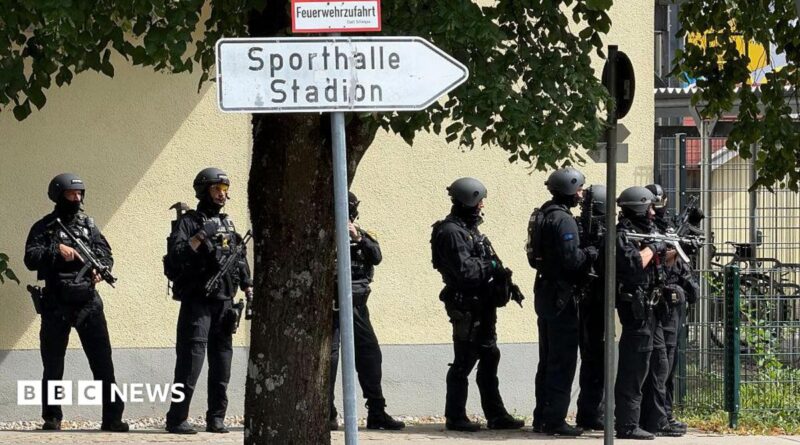 Police officers stand with guns outside a school in Germany.