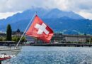 A view of a Swiss flag on a boat on lake Lucerne and Lucerne city in central Switzerland