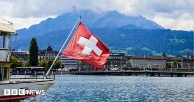 A view of a Swiss flag on a boat on lake Lucerne and Lucerne city in central Switzerland
