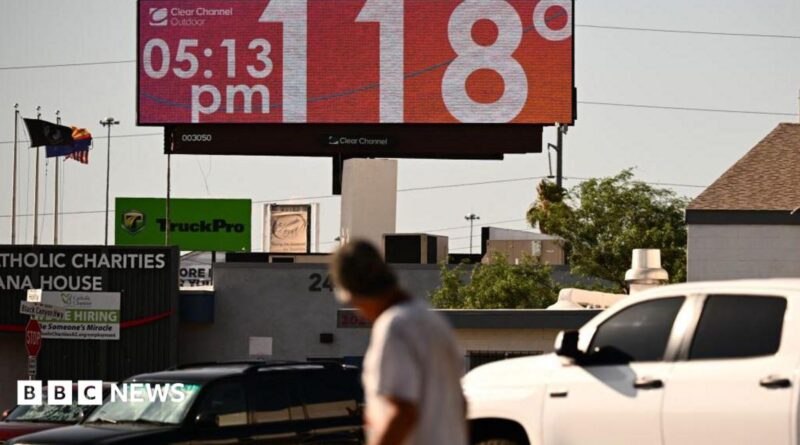 Man walks through road and looks up at sign that says 118 degrees and 05:15 pm
