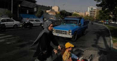 A woman and girl cross a street in central Tehran on July 22, 2026