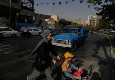 A woman and girl cross a street in central Tehran on July 22, 2026