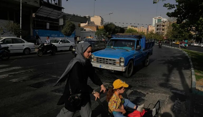 A woman and girl cross a street in central Tehran on July 22, 2026
