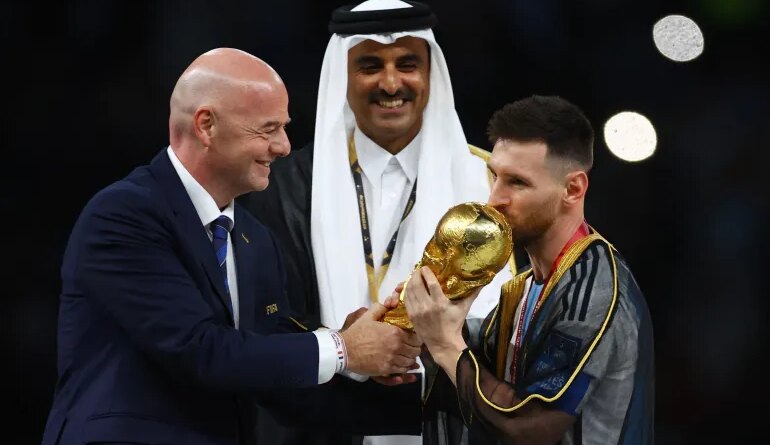 Soccer Football - FIFA World Cup Qatar 2022 - Final - Argentina v France - Lusail Stadium, Lusail, Qatar - December 18, 2022 Argentina's Lionel Messi kisses the trophy as he is presented it by FIFA president Gianni Infantino alongside Emir of Qatar Sheikh Tamim bin Hamad Al Thani REUTERS/Kai Pfaffenbach