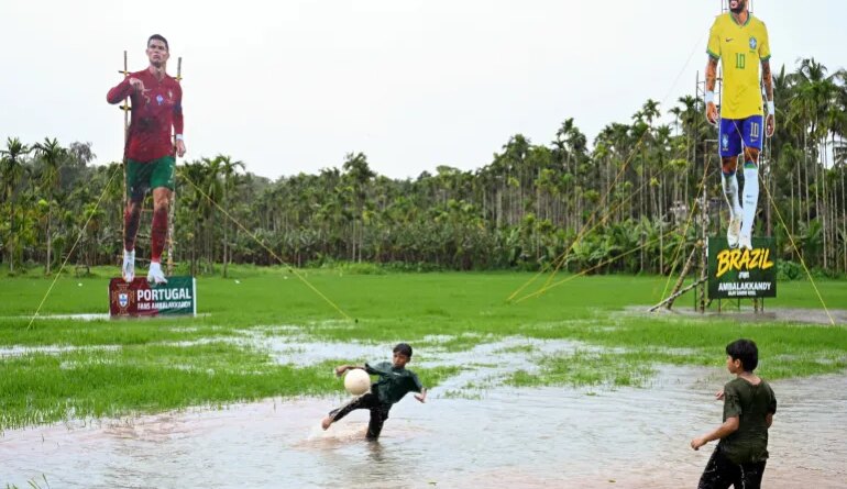 Children play football in front of cutouts of Portugal’s Cristiano Ronaldo and Brazil’s Neymar Jr put up by supporters ahead of the 2026 FIFA World Cup, in Kozhikode, India, on June 9, 2026