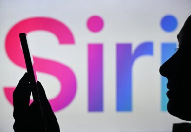 An image of a woman holding a cell phone in front of the Siri logo displayed on a computer screen.