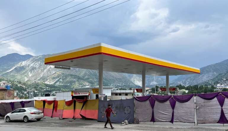 A man walks past a closed fuel station with the entrance blocked off by a cloth in the background, during a shutdown strike called by the recently banned Joint Awami Action Committee (JAAC), an alliance of civil society groups, in Muzaffarabad, Pakistani Kashmir, June 19, 2026. Picture taken with a mobile phone. REUTERS/Naseer ud Din