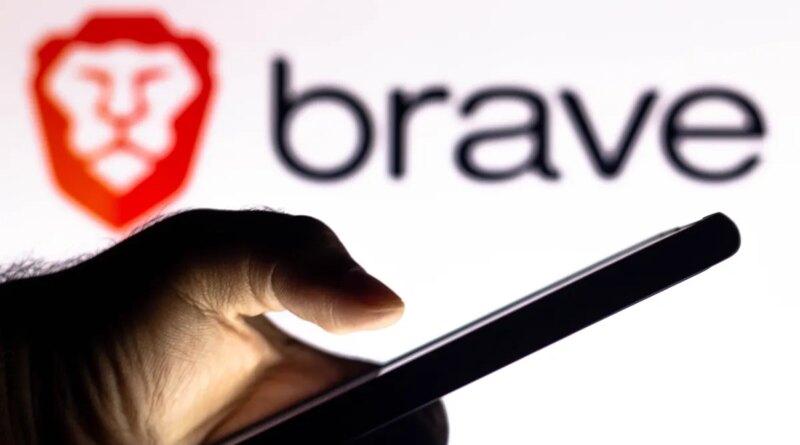 In this photo illustration, a hand of a person holds a smartphone with a Brave Browser logo displayed in the background.