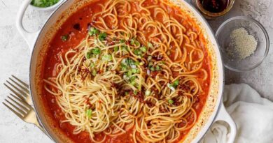 Chili crunch pasta served with green onions, sesame seeds, and extra chili crunch.