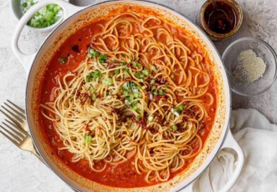 Chili crunch pasta served with green onions, sesame seeds, and extra chili crunch.