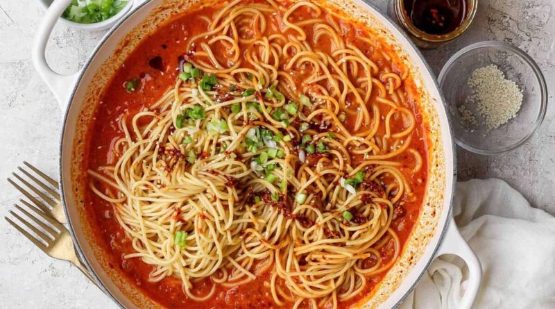 Chili crunch pasta served with green onions, sesame seeds, and extra chili crunch.