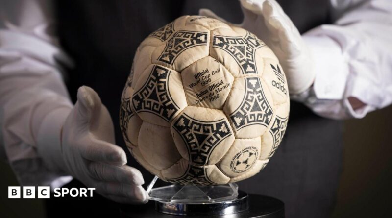 A person wearing white gloves places the football used in the 1986 World Cup quarter-final on a stand
