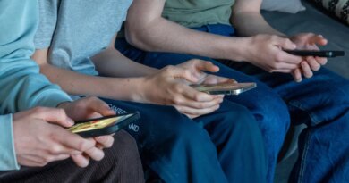 Three teenage boys look at their smartphone screens.