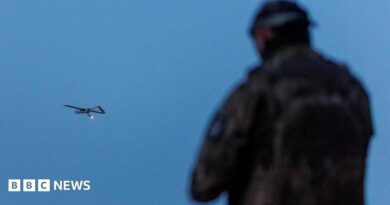 A Ukrainian soldier operating a drone, which is flying in the air in the background